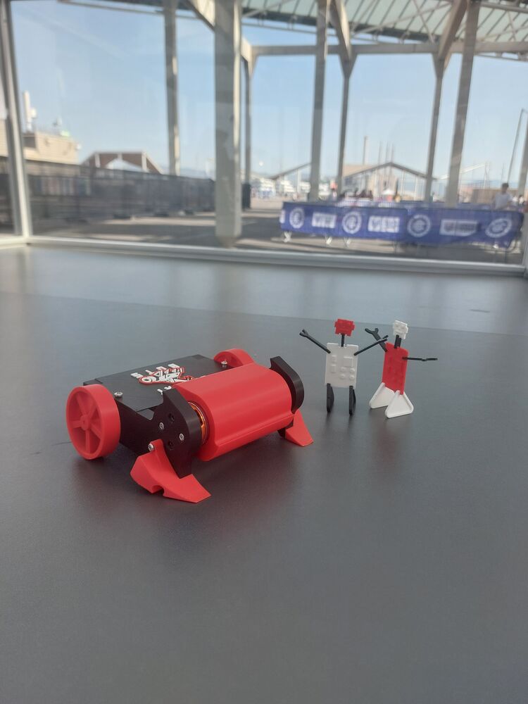 El robot rojo del kit en la arena, con dos figuritas de juguete a su lado