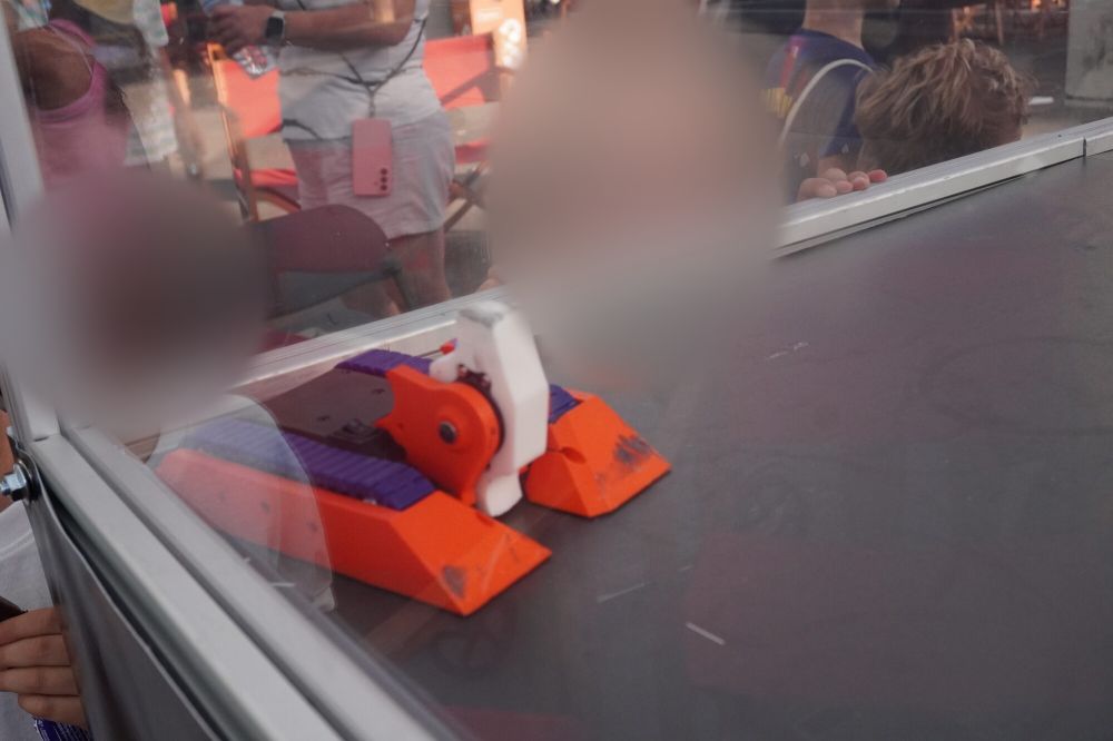 Un niño con la cara pegada al cristal, a un palmo de un robot naranja