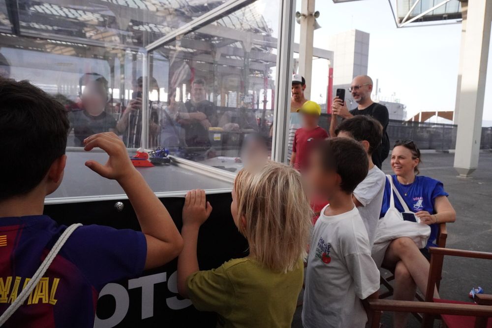 Tres niños con las manos en el cristal de la arena