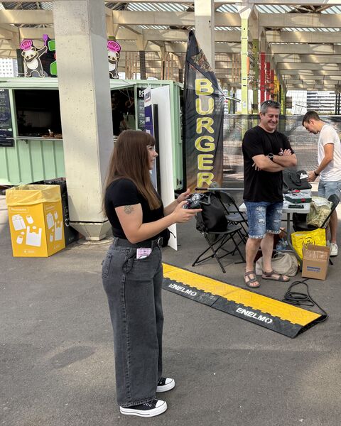 Irina, con el mando, junto a la arena y con el robot COMBATBOTS sobre la mesa