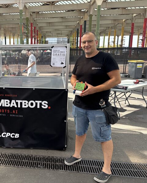 El piloto de ElPLAitor, con el robot verde en la mano, junto a la arena