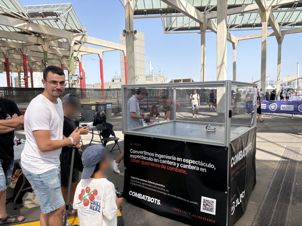 Un piloto enseña a un niño a manejar el robot junto a la arena
