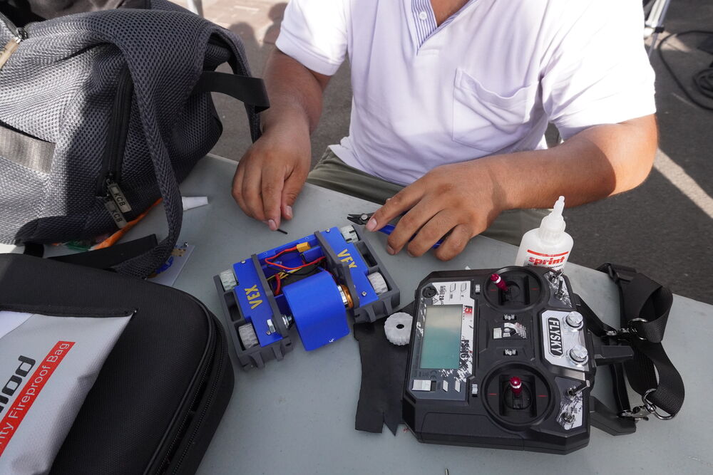 Manos reparando el robot Vex con la emisora al lado