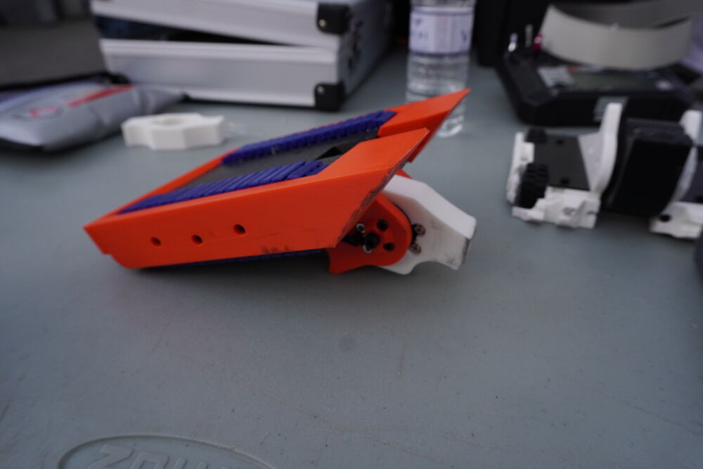 Una cuña naranja impresa en 3D con las orugas azules, de cerca