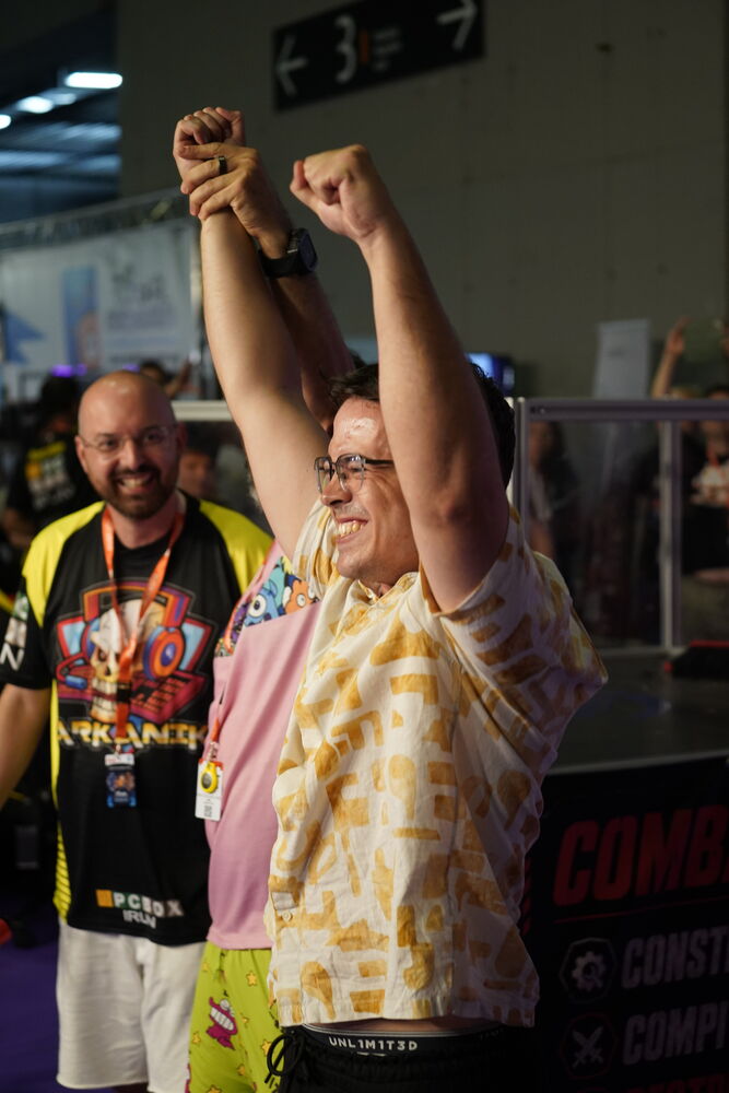 El ganador celebra con los brazos en alto junto a la arena