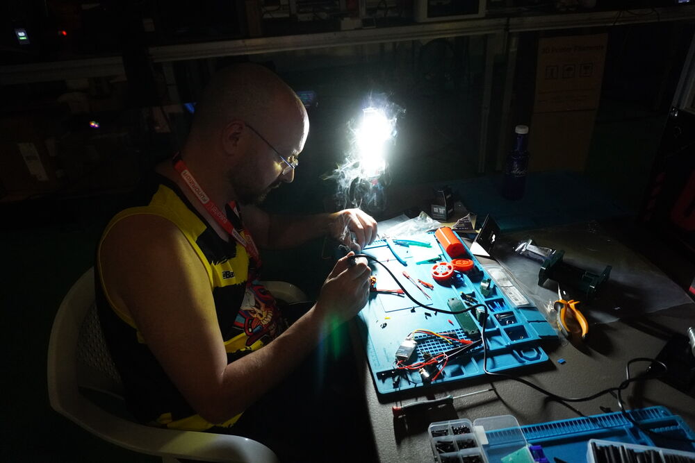 Alguien soldando la electrónica de un robot de madrugada